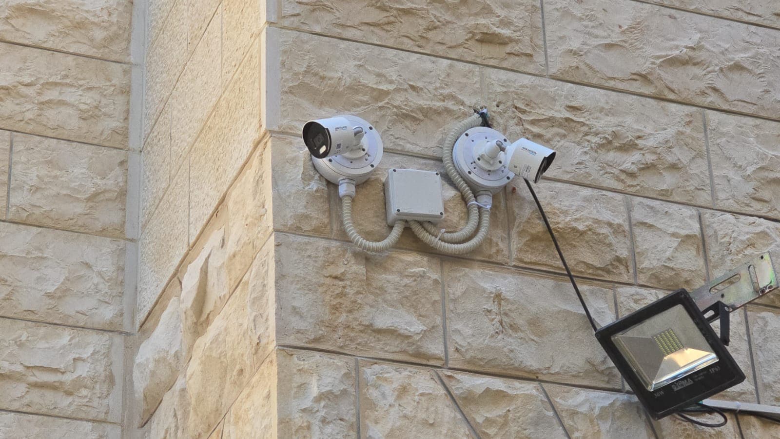 שתי מצלמות Hikvision מותקנות על קיר אבן עם צנרת מוגנת