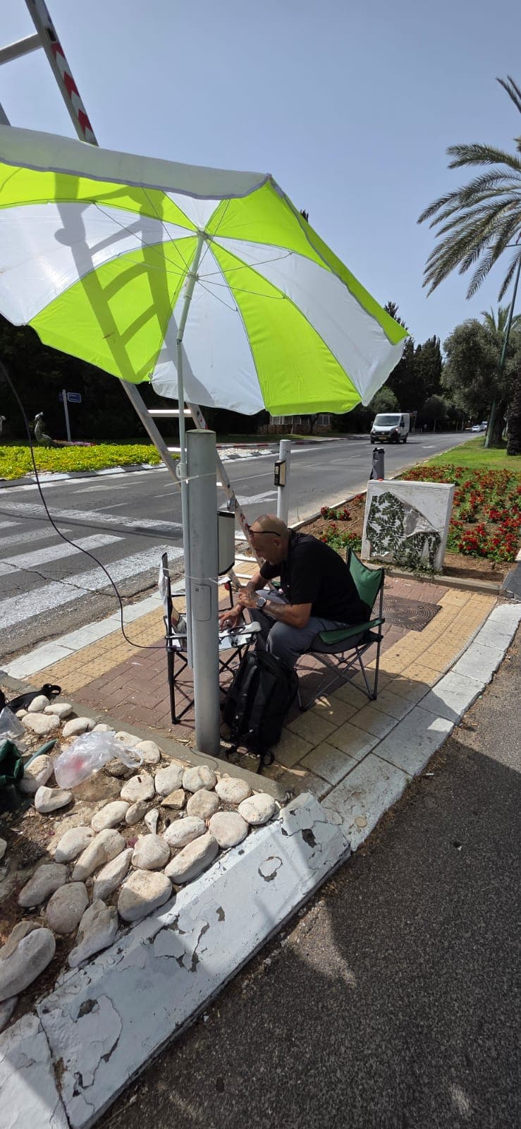 טכנאי עובד בצל שמשייה על ארון בקרה בצומת עירוני